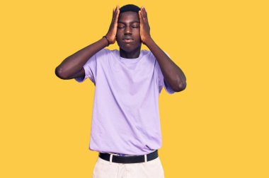 Genç Afro-Amerikan adam gündelik kıyafetler giyiyor. Baş ağrısı çekiyor, çaresiz ve stresli. Çünkü acı ve migren ağrısı var. Eller başının üstünde.. 