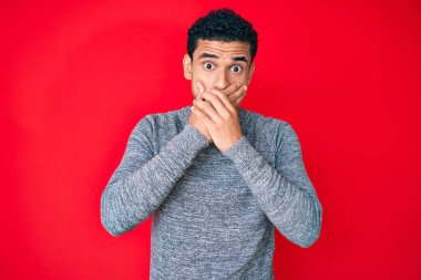 Kırmızı zemin üzerinde genç yakışıklı İspanyol adam yanlışlıkla elleri ile ağzını kapatırken şok oldu. gizli kavram. 