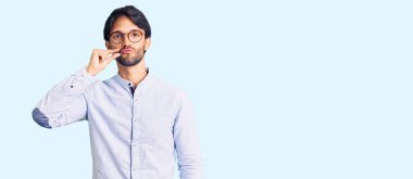 İş gömleği giyen, gözlüklü, ağzı ve dudakları parmaklarıyla kapanan yakışıklı bir İspanyol. gizli ve sessiz, tabu konuşması 