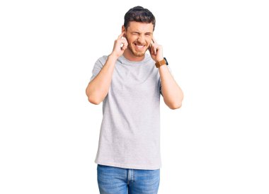 Gürültülü müzik sesi için kulakları parmaklarıyla kulaklarını kapatan ayı tişörtlü yakışıklı genç adam. sağır kavramı. 