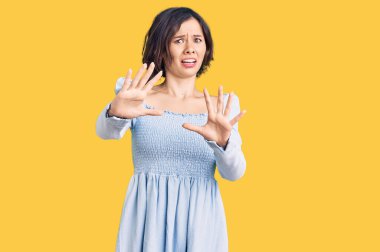 Genç ve güzel bir kız günlük kıyafetler giyiyor. Korkudan ödü patlıyor ve korkuyor. El hareketlerini durdur, şok içinde bağır. panik konsepti. 