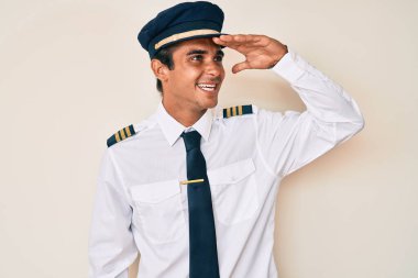 Uçak pilotu üniforması giyen genç İspanyol adam çok mutlu ve gülümsüyor. arama kavramı. 