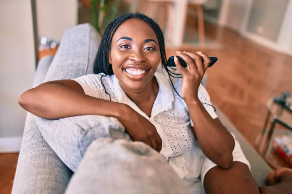 Joven Mujer Afroamericana Sonriendo Feliz Sentado Usando Teléfono Inteligente Casa —  Fotos de Stock