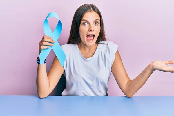 Young Caucasian Woman Holding Blue Ribbon Celebrating Achievement Happy Smile — Stock Photo, Image