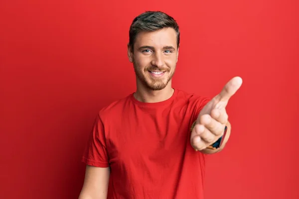 英俊的高加索男人穿着休闲的红色T恤 微笑友善地握手表示问候和欢迎 成功的商业 — 图库照片