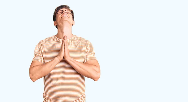 Молодой Красивый Мужчина Повседневной Одежде Очках Умоляя Молясь Руками Вместе — стоковое фото
