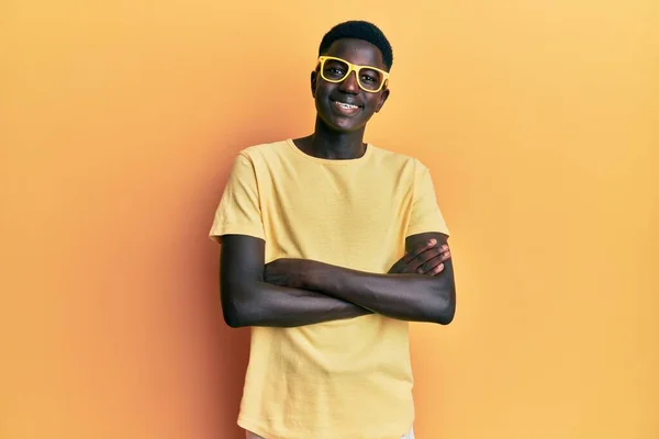 Młody Afroamerykanin Luźnych Ciuchach Okularach Uśmiechnięty Skrzyżowanymi Ramionami Patrzący Kamerę — Zdjęcie stockowe