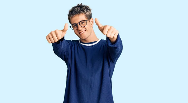 年轻英俊的男人穿着休闲装 戴着眼镜 肯定用手做积极的手势 微笑着竖起大拇指 为成功感到高兴 优胜手势 — 图库照片