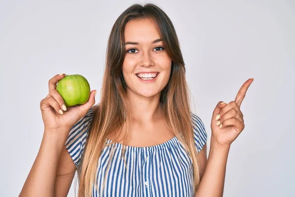 側に手と指で幸せなポインティング緑のリンゴの笑顔を保持美しいCaucasian女性 — ストック写真