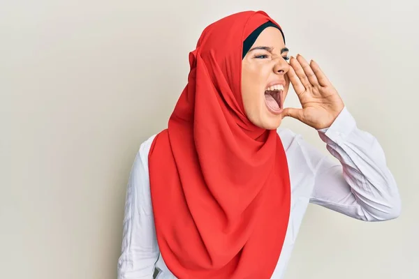 伝統的なイスラム教のヒジャーブスカーフを身に着けている若い美しいヒスパニックの女の子は大声で叫び 口の中で手で横に大声で叫ぶ コミュニケーションの概念 — ストック写真