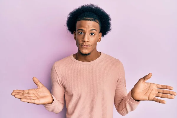 African american man with afro hair wearing casual clothes clueless and confused with open arms, no idea and doubtful face.