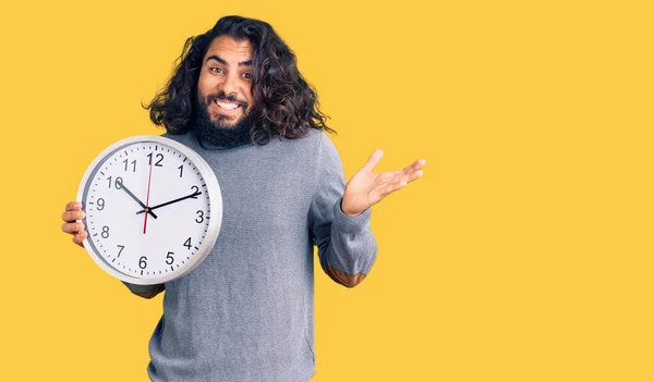 Hombre Árabe Joven Sosteniendo Gran Reloj Celebrando Victoria Con Sonrisa —  Fotos de Stock