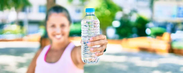 中世のスポーツ女性は公園で幸せな保持ボトルの水を笑っています — ストック写真