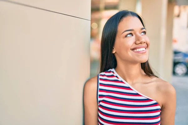 若いですラテン語の女の子笑顔幸せそうに街の壁にもたれて — ストック写真