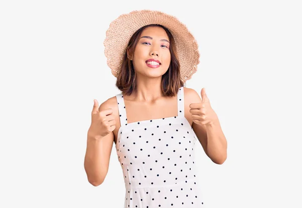 年轻美丽的中国姑娘戴着夏帽 成功地做了一个积极的手势 微笑着竖起大拇指 快乐地微笑着 快乐的表达和胜利的姿态 — 图库照片