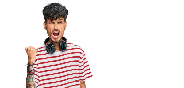 Joven Hombre Hispano Escuchando Música Usando Auriculares Enojado Loco Levantando —  Fotos de Stock