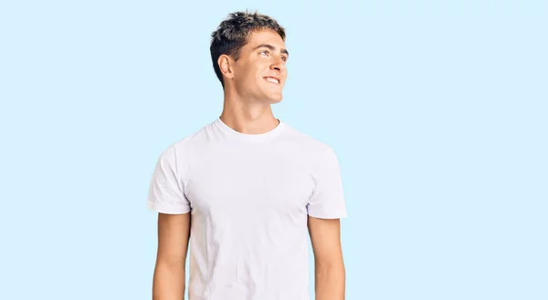 年轻英俊的男子穿着随意的白色T恤 面带微笑 表情自然地朝一边看去 充满自信地大笑 — 图库照片
