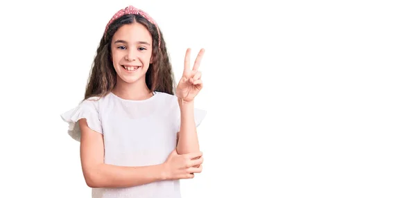 可爱的惊慌失措的小女孩穿着随意的白色T恤 开心地微笑着 用手指在镜头前眨眼示意胜利 第二点 — 图库照片