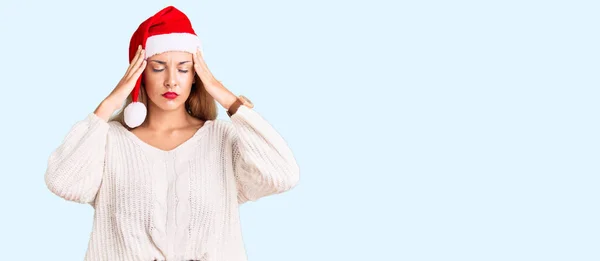 痛みや片頭痛のために必死に頭痛やストレスに苦しんでクリスマスの帽子を身に着けている美しい若い女性 手を頭に — ストック写真