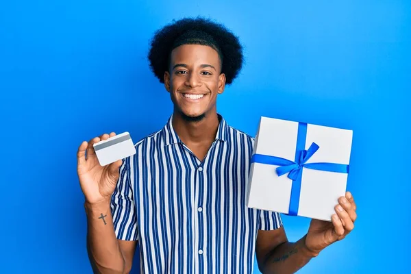 Hombre Afroamericano Con Cabello Afro Sosteniendo Regalo Tarjeta Crédito Sonriendo —  Fotos de Stock