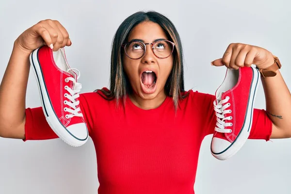 Chica Latina Joven Sosteniendo Zapatos Casuales Rojos Enojado Loco Gritando —  Fotos de Stock