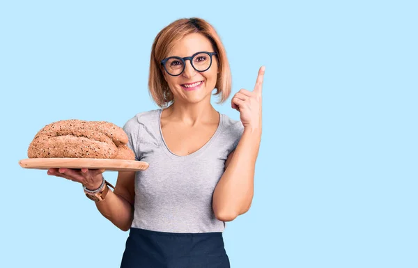 Jovem Loira Segurando Pão Integral Surpreso Com Uma Ideia Pergunta — Fotografia de Stock