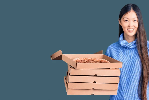 若い美しい中国人女性を保持段ボール箱のイタリアのピザ驚きでアイデアや質問を指差す指で幸せな顔 ナンバーワン — ストック写真