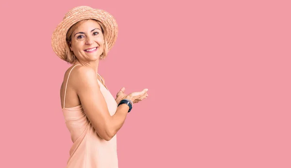 若いですブロンド女性身に着けています夏の帽子ポインティング脇に手オープン手のひらショーコピースペース 提示広告笑顔興奮幸せな — ストック写真