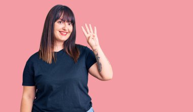 Genç ve cüsseli bir kadın dört numarayı gösterip gösterirken kendinden emin ve mutlu gülümsüyor.. 