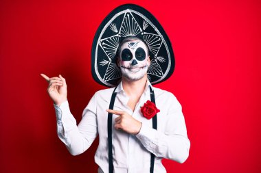 Ölü kostümün giyildiği gün yüzünde mutlu ve havalı bir gülümsemeyle parmaklarını yana doğru gösteren bir adam. diş gösterme. 