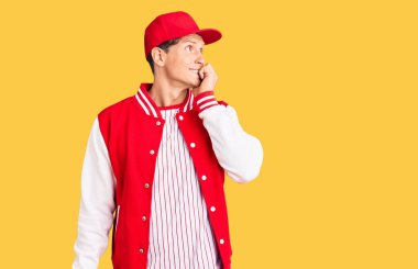 Beyzbol forması giyen yakışıklı bir genç stresli ve gergin görünüyor. Ağzı tırnak yiyen ellerle. anksiyete. 