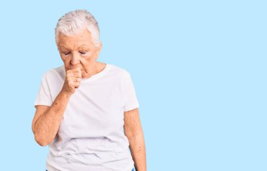 Mavi gözlü, gri saçlı, sıradan beyaz tişörtlü, kendini kötü hisseden ve soğuk algınlığı veya bronşitin belirtisi olarak öksüren son sınıf güzeli. sağlık hizmeti kavramı. 