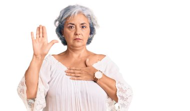 Senior woman with gray hair wearing bohemian style swearing with hand on chest and open palm, making a loyalty promise oath  clipart