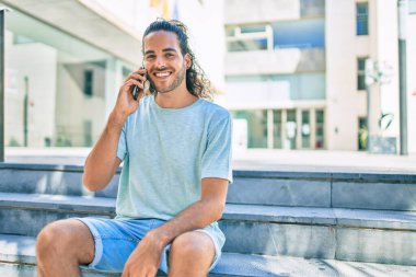 Genç İspanyol adam gülümsüyor. Şehirdeki akıllı telefondan konuşuyor..