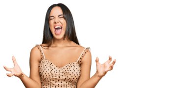 Seksi parti elbisesi giymiş genç, İspanyol bir kız. Deli gibi bağırıyor, agresif bir ifadeyle bağırıyor ve kollarını kaldırıyor. hüsran kavramı. 