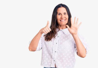 Genç, güzel, esmer, rahat gömlekli bir kadın. Altıncı parmaklarını gösterip gösterirken, kendinden emin ve mutlu bir şekilde gülümsüyor.. 