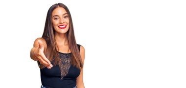 Genç İspanyol kadın günlük kıyafetler giyip gülümseyerek selamlaşma ve dostça tokalaşma sunuyor. başarılı iş. 