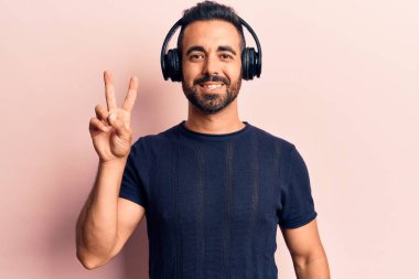 Genç İspanyol adam müzik dinliyor kulaklık takıyor kameraya gülümseyen bir gülümsemeyle zafer işareti yapıyor. İki numara.. 