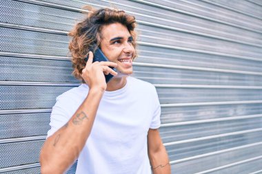 Genç İspanyol adam şehrin caddesinde akıllı telefondan konuşuyor.