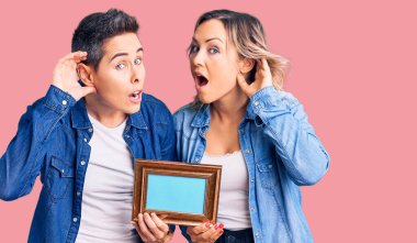 Boş bir çerçeve tutan, ağzı kulaklarında gülümseyen iki kadın dedikoduları ve dedikoduları dinliyor. Sağırlık kavramı. 