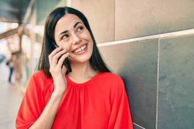 Genç Latin kız gülümsüyor. Şehirdeki akıllı telefondan konuşuyor..