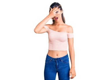 Genç ve güzel bir kadın günlük giysiler içinde şok içinde yüzünü ve gözlerini kapayarak utangaç ifadesiyle parmaklarının arasından bakıyor.. 