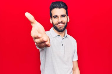 Sakallı, sıradan polo giyen, dostça gülümseyen ve selamlaşan genç yakışıklı bir adam. başarılı iş. 