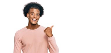 Afro saçlı, sıradan kıyafetler giyen mutlu yüzüyle gülümseyen ve baş parmağıyla yüzünü gösteren Afro-Amerikan bir adam.. 