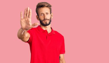 Sıradan kıyafetler giyen sakallı yakışıklı sarışın adam avucunun içi gibi şarkı söylemeyi kesiyor. Yüzünde olumsuz ve ciddi bir jest olan uyarı ifadesi. 