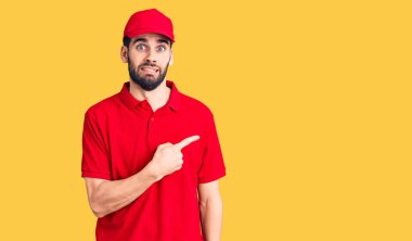 Sakallı, teslimat üniforması giyen genç ve yakışıklı bir adam endişeli ve endişeli bir ifade takınıyor. 