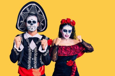 Arka planda Meksika kostümlü genç çift başarı için heyecanlı kolları havada ve gözleri kapalı zaferi kutlarken gülümsüyor. Kazanan konsept. 