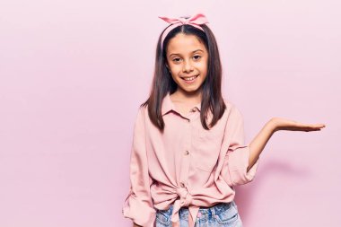 Güzel kız günlük kıyafetler giymiş neşeli bir şekilde gülümseyen ve avuç içi kameraya bakan.. 