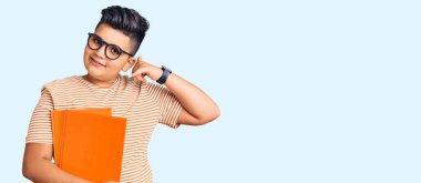 Küçük çocuk kitap tutuyor gözlük takıyor gülümsüyor telefonla el ve parmaklarıyla jest yapıyor telefonda konuşuyor gibi. iletişim kavramları. 