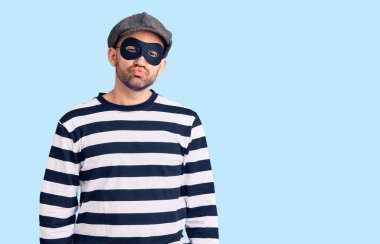 Hırsız maskesi takmış genç yakışıklı bir adam kameraya bakıyor ve güzel ve seksi bir şekilde havaya bir öpücük yolluyor. aşk ifadesi. 